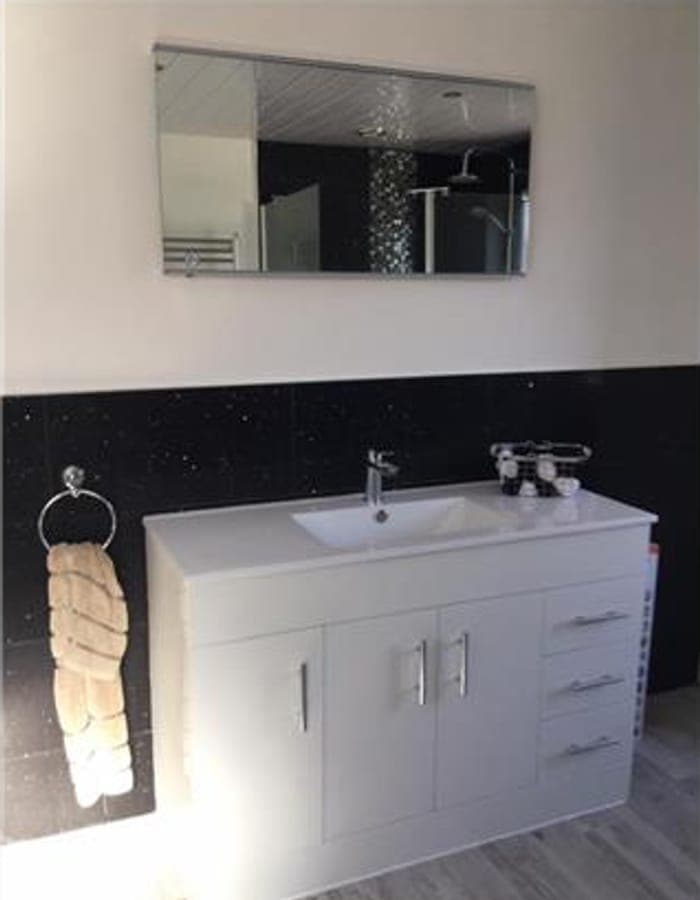 A white vanity unit and basin below a mirror