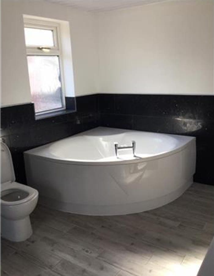 A white corner bath against a black feature wall