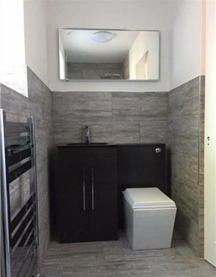 A dark wood vanity unit and toilet in a tiled bathroom