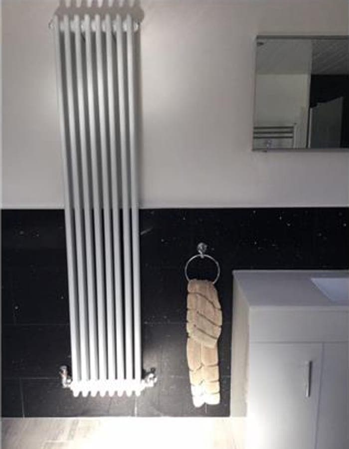 A chrome column radiator on a black feature wall