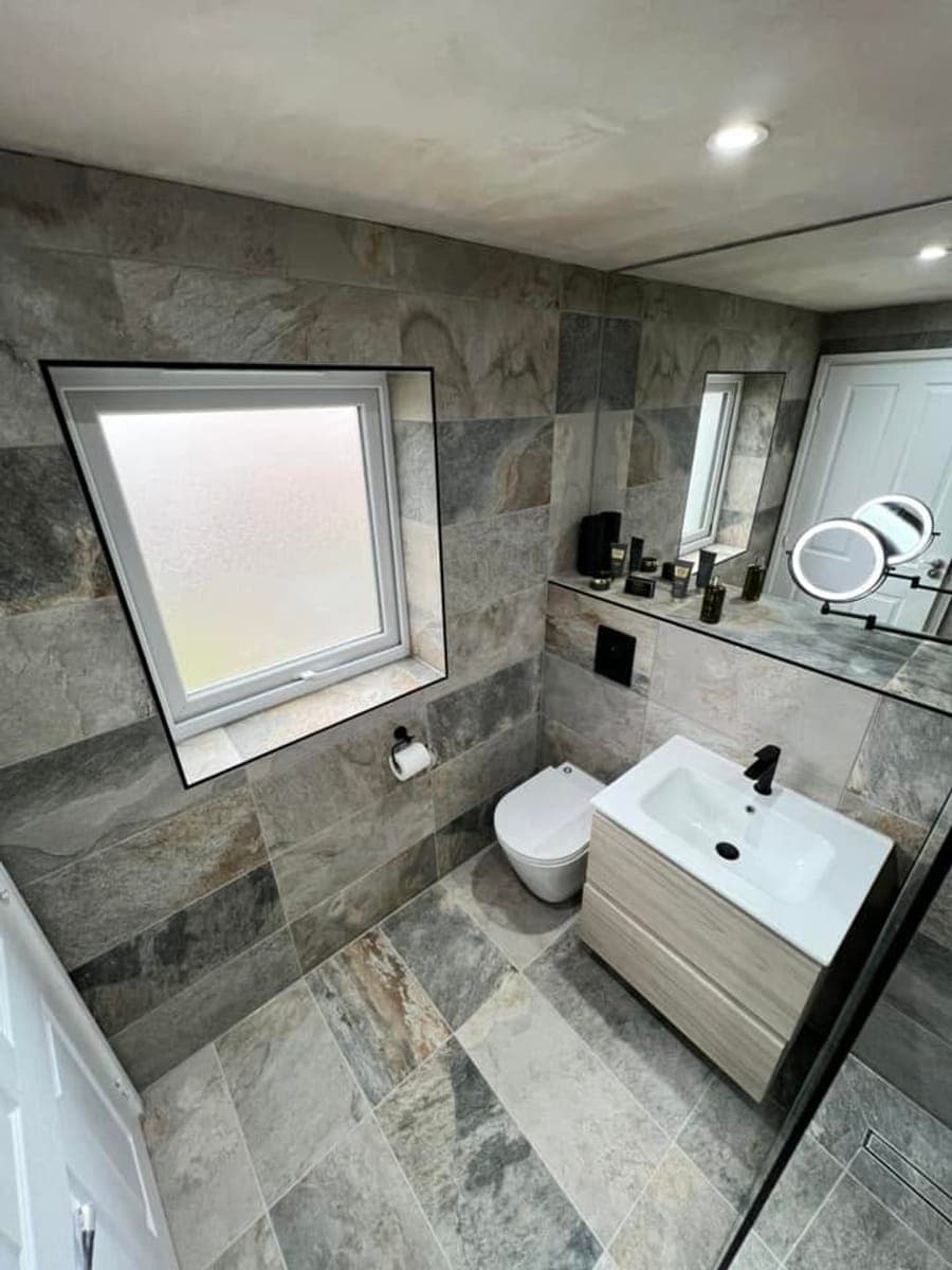 A slate tiled bathroom with a wall hung toilet and vanity