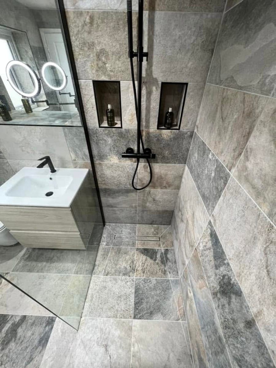 A grey slate tiled wet room with a level access shower and matt black fittings