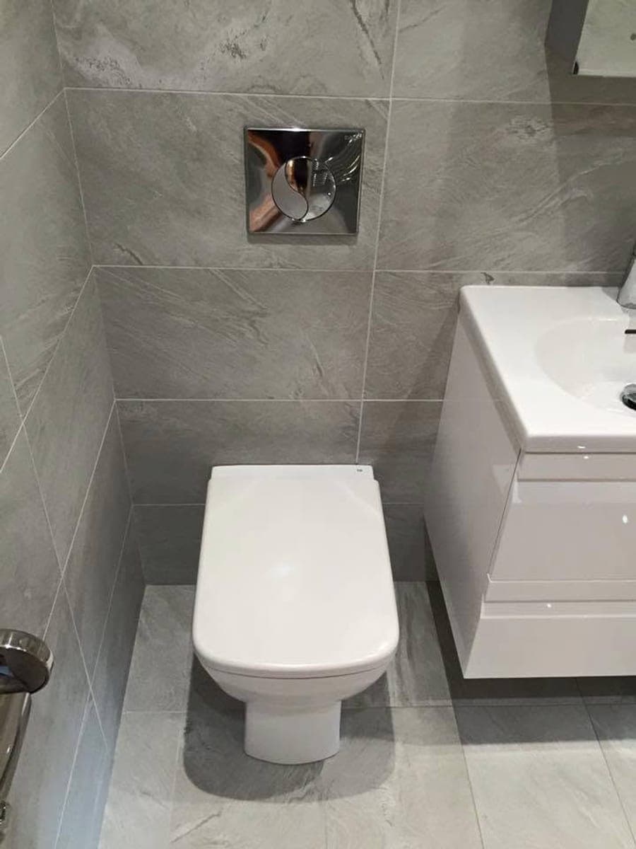 A wall hung vanity unit and toilet in a grey tiled room
